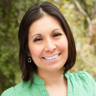 Professional woman smiling outdoors in a natural light headshot, representing a Belle Vie Travel client testimonial.